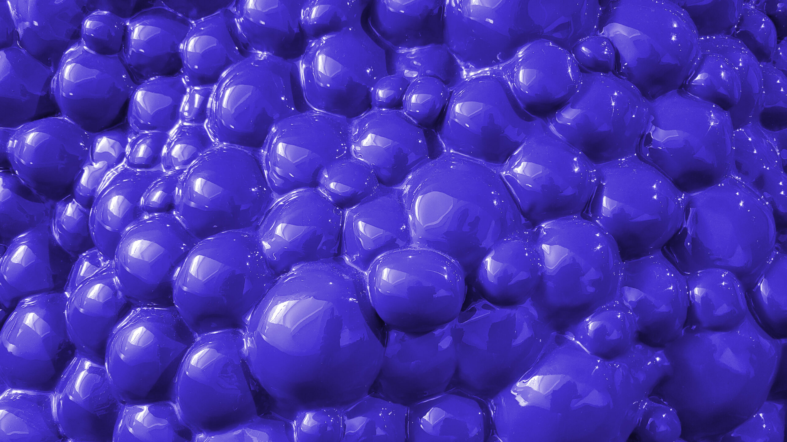 Close-up macro shot of transparent soap bubbles forming a complex, interconnected pattern with a bluish tint.