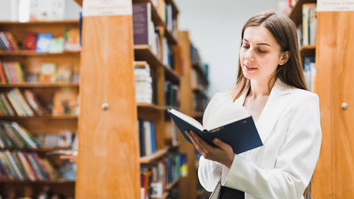 Academic librarian reading a book in a university library, promoting research and image integrity best practices.